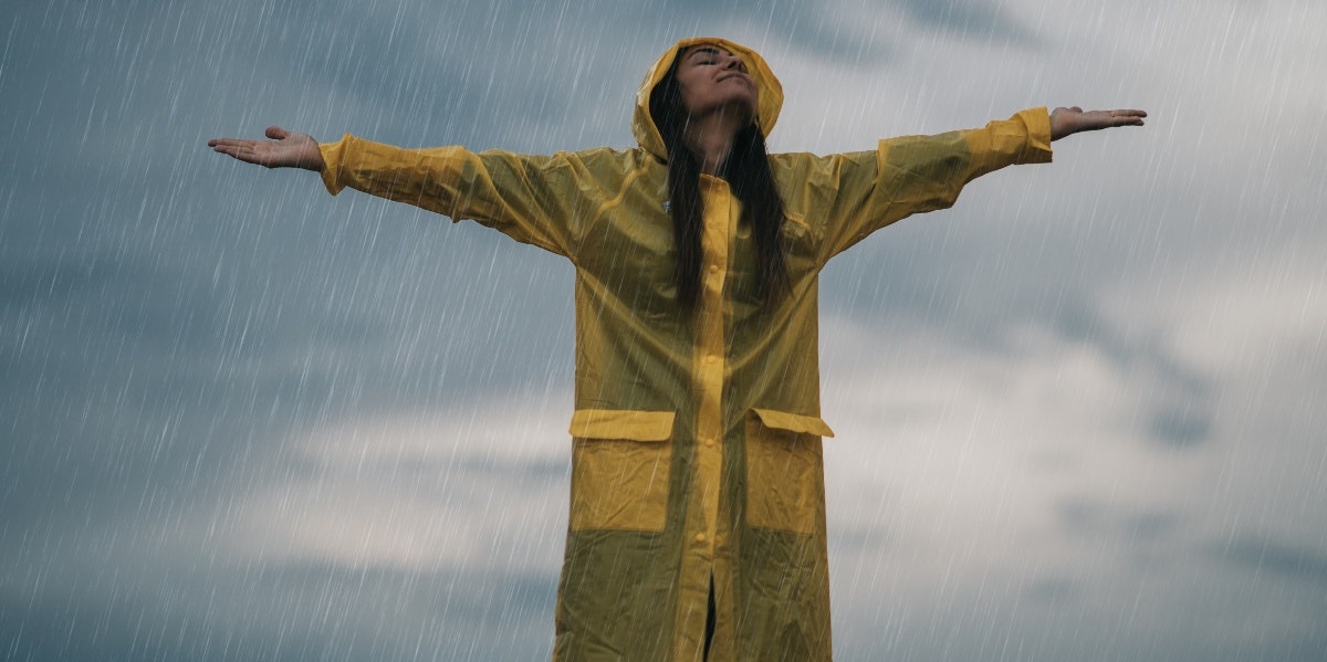 30 Best Songs About Rain woman in raincoat standing in the rain