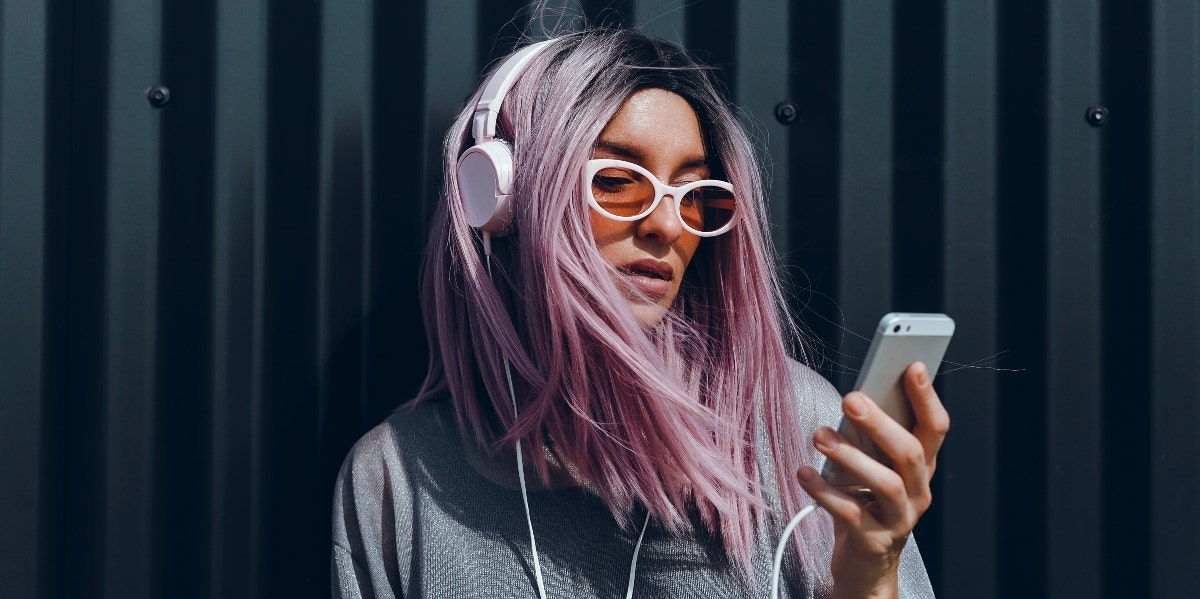 15 Songs About Deserving Better In A Relationship woman with purple hair listening to music on her phone