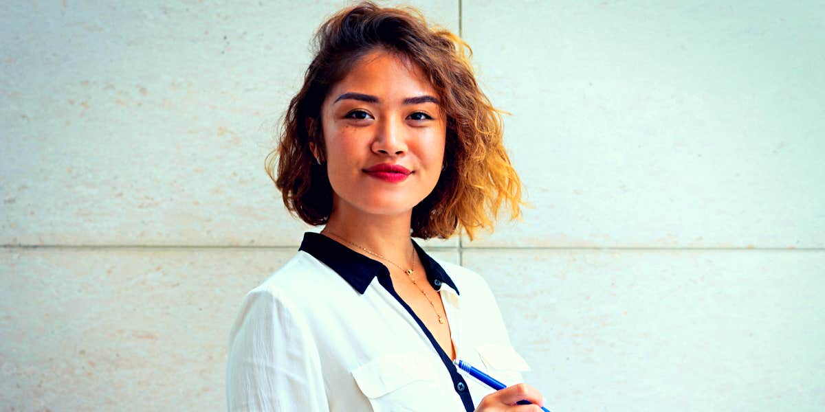 Young Asian professional woman standing confidently and smiling at the camera 