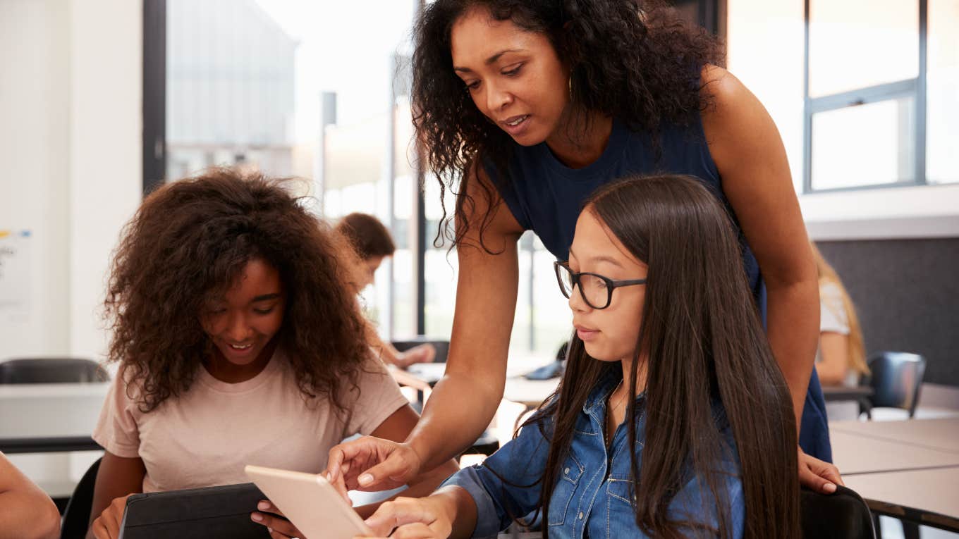 Teacher helping high school students in classroom at school