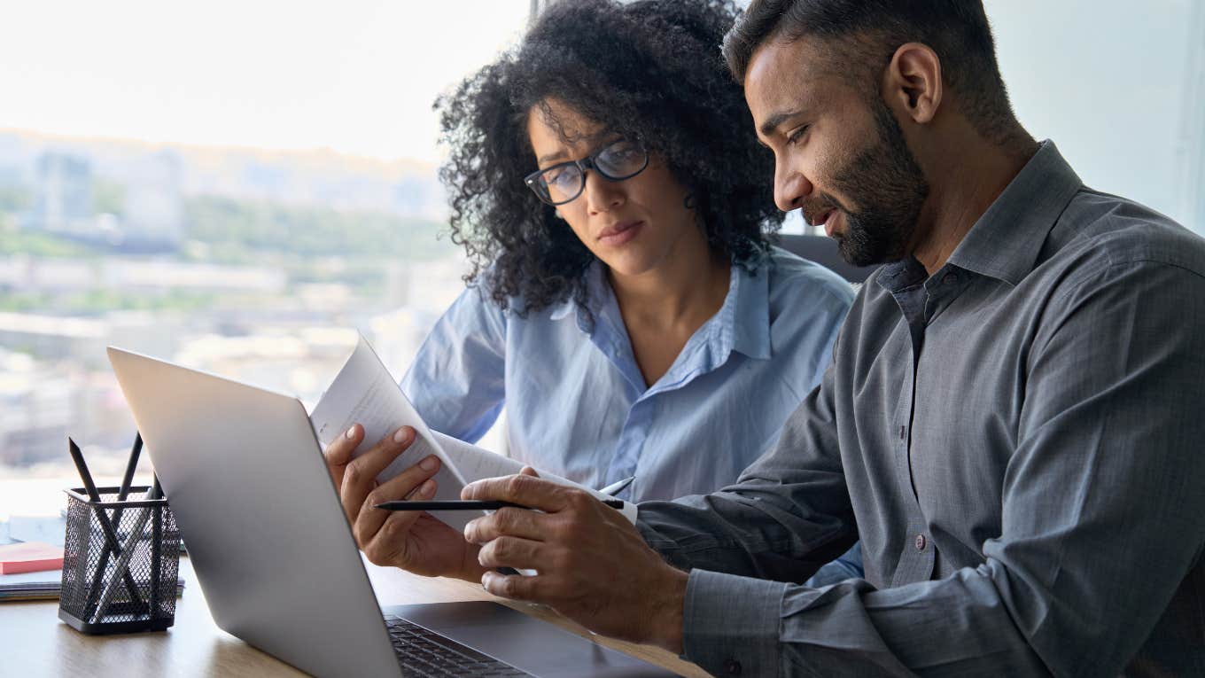 businesspeople sitting at desk with laptop doing paperwork together discussing project