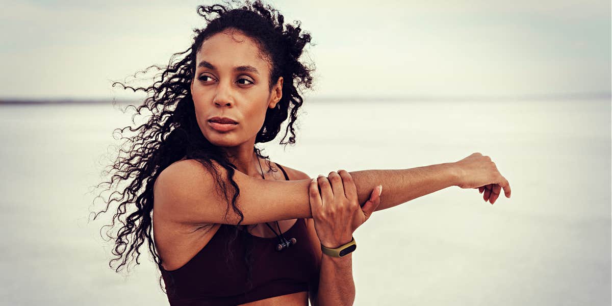 Black woman athlete stretching and looking very serious outdoors