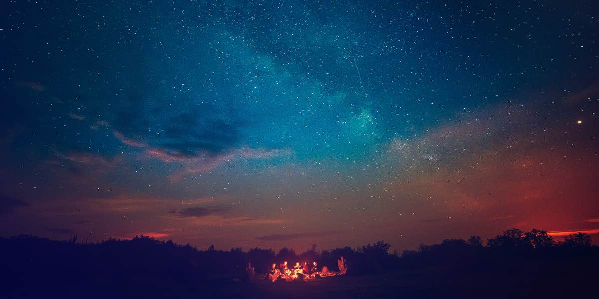 campers under the night sky with a shooting star