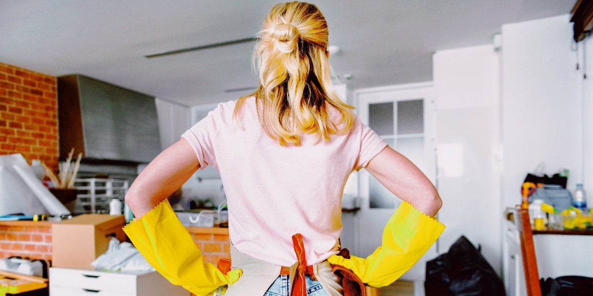 spring cleaning woman with cleaning gloves looking at mess