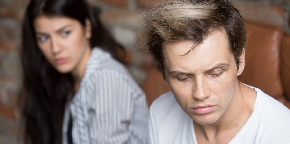 upset man looking away from woman behind him