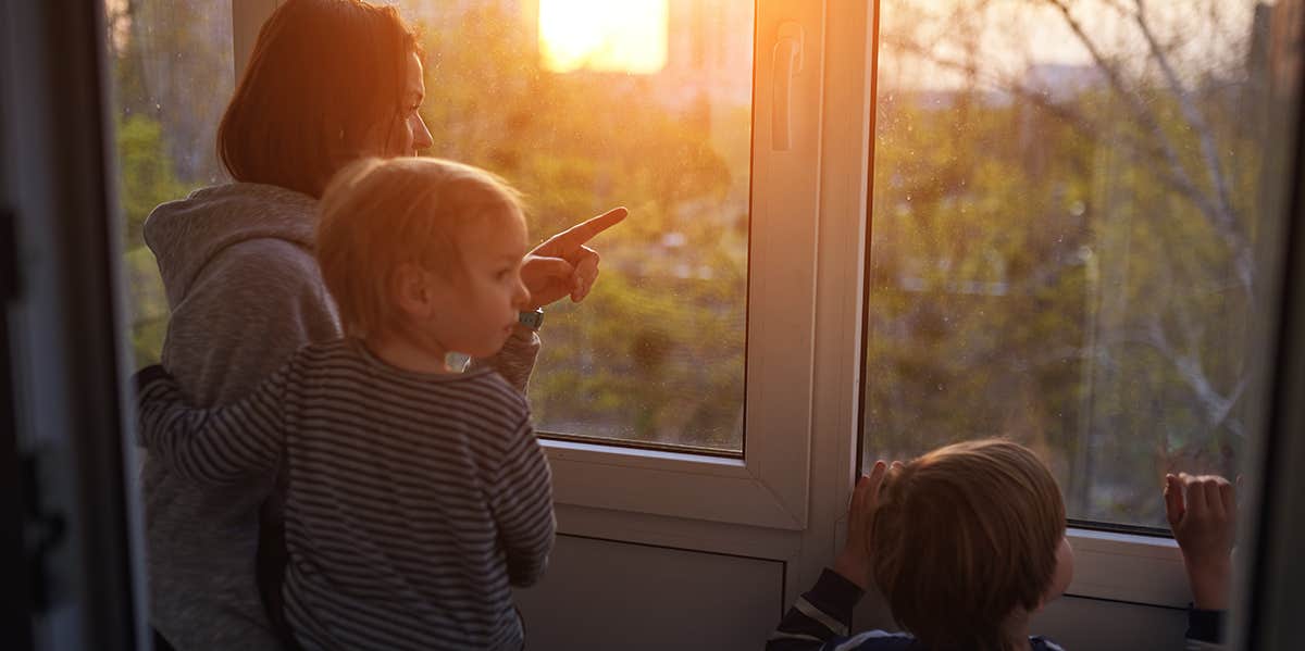 stay at home mom looking out the window with her two kids