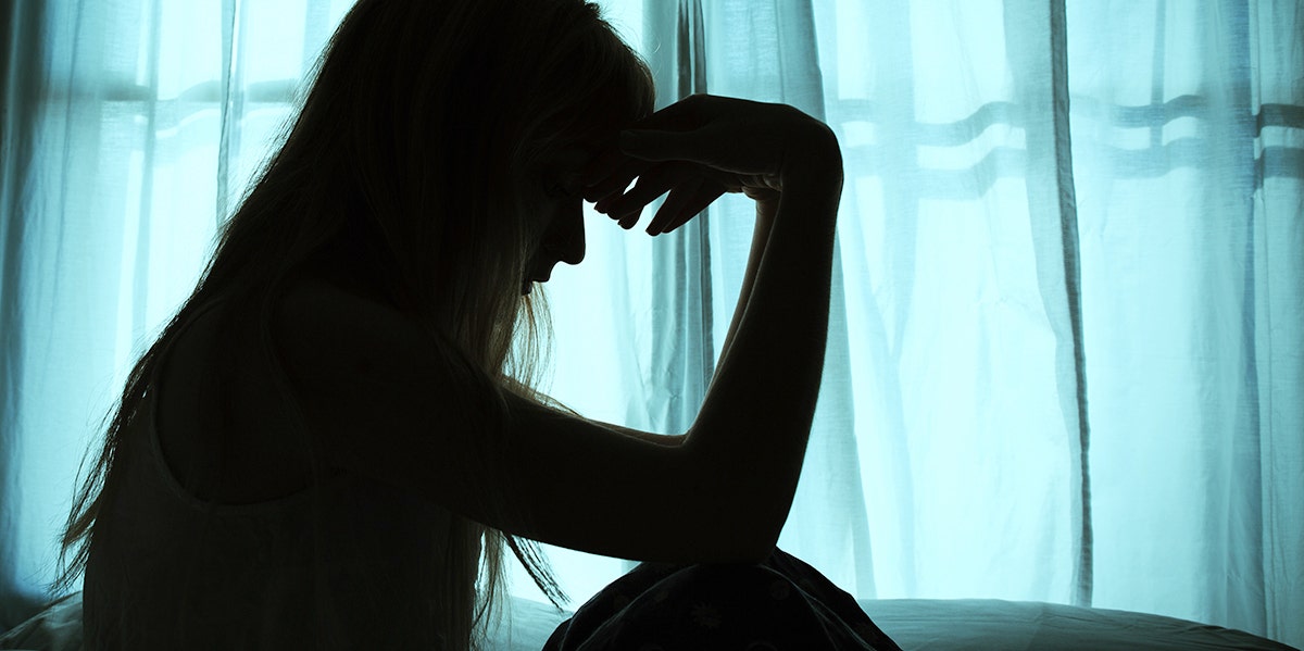 woman in shadow with hands on forehead