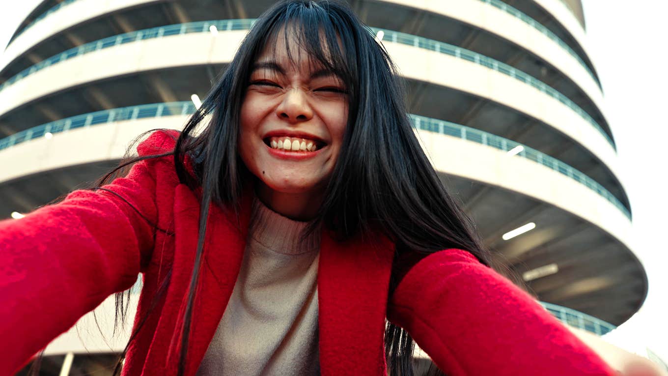 smiling woman taking photo with tall building