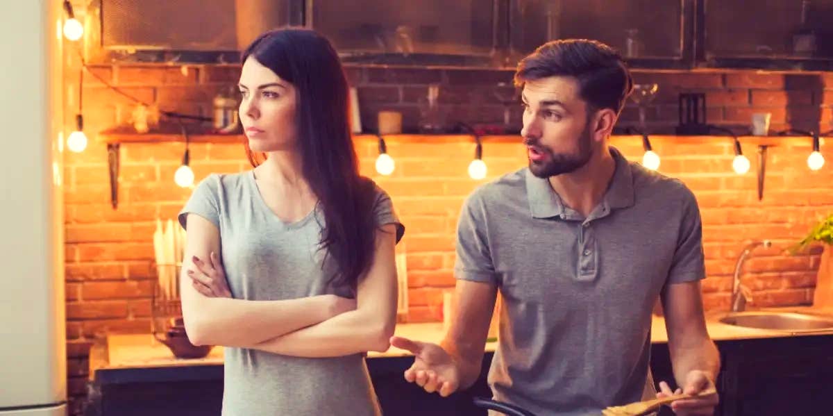 man trying to talk to woman with crossed arms looking in other direction