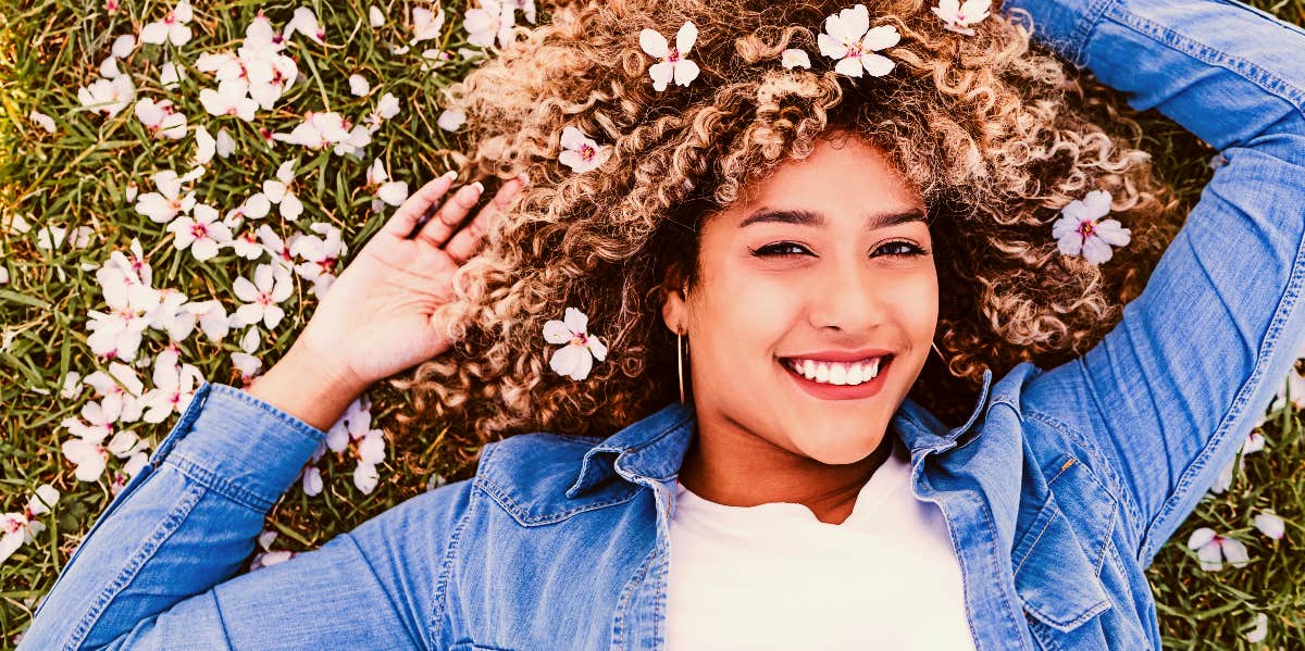 woman smiling in the grass with flowers around her