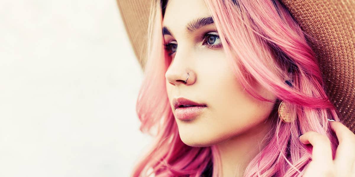 young woman with pink hair and hat, looking away