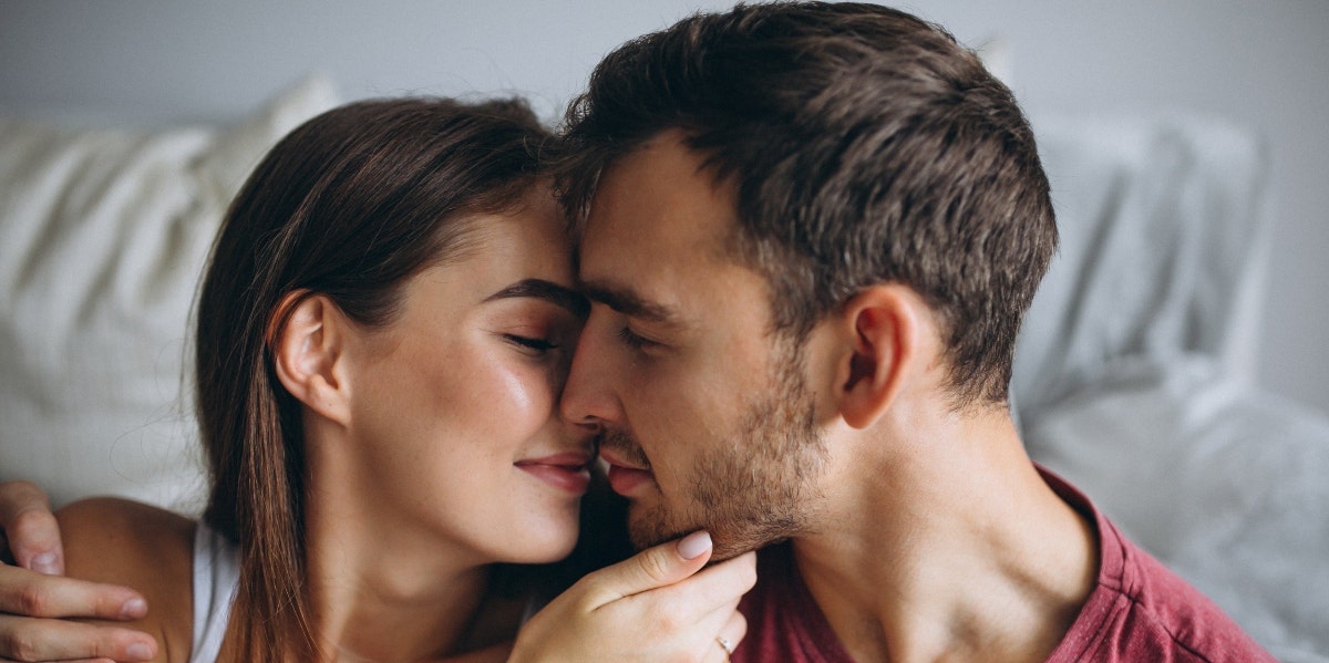 man and woman kissing in bed