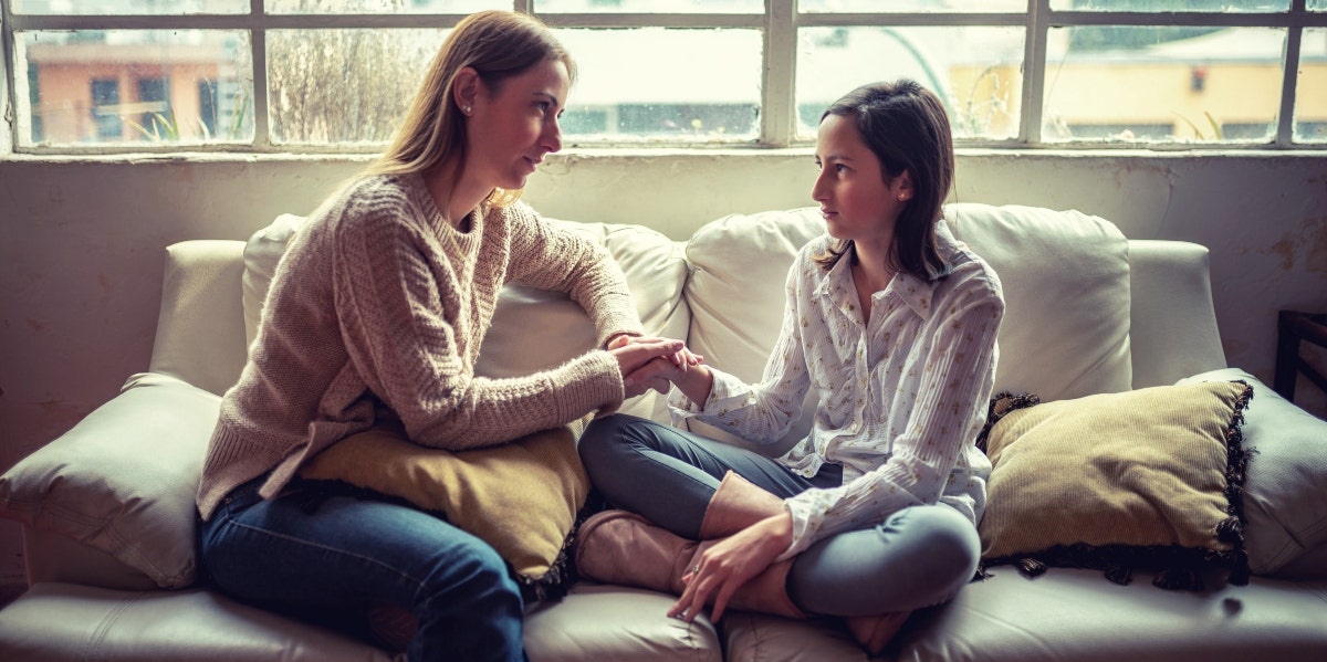 stressed kid mom talking to daughter on couch