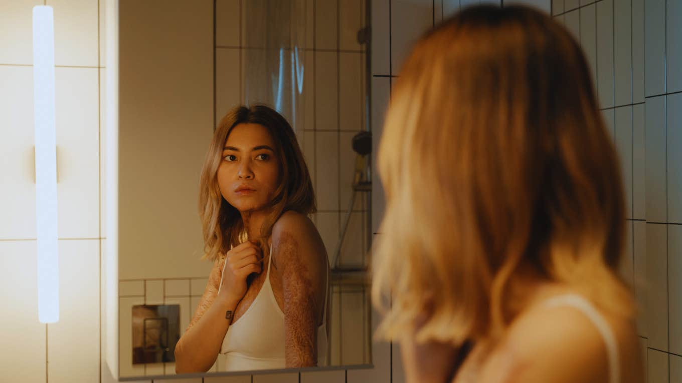 The Unique Struggle Of People Who Were Parented But Not Mothered woman who was parented but not mothered looking in mirror