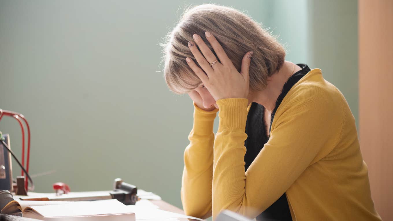 teacher sitting at her desk looking down in dismay