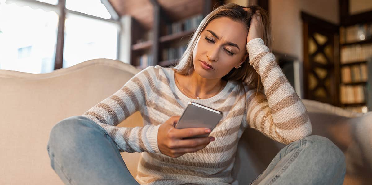 woman looking at iphone with head in hand