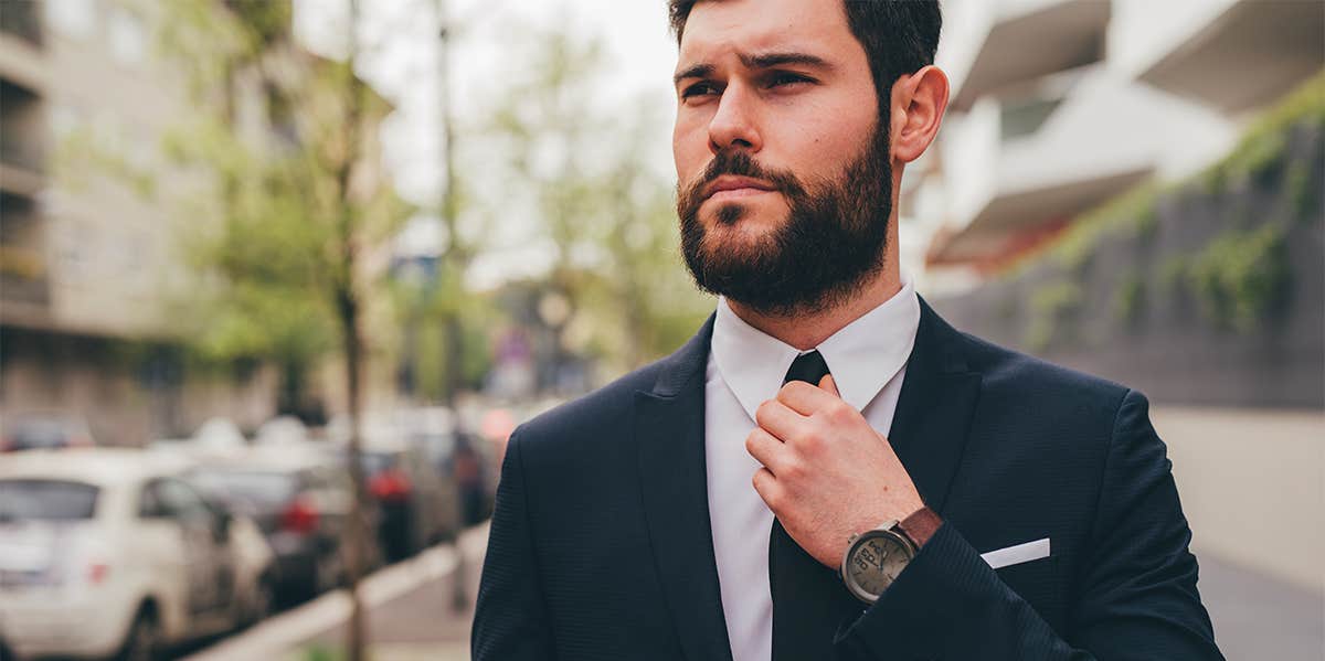 successful man in suit adjusting tie