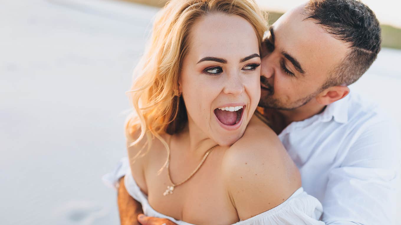 young guy kisses a beautiful fun woman on the beach