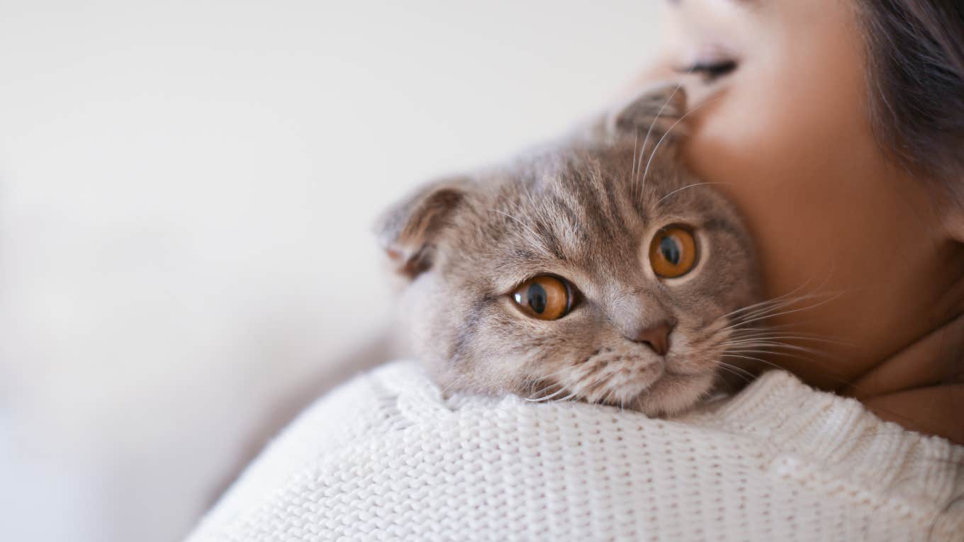 woman with cat resting on her shoulder