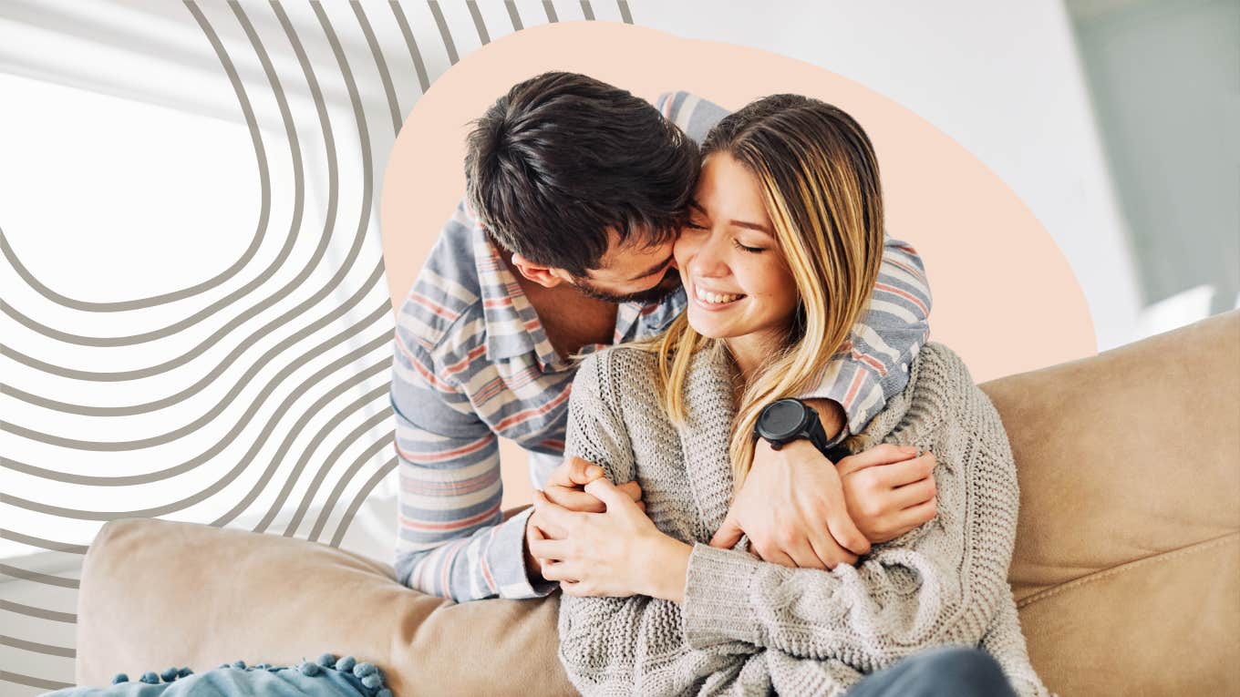 man wrapping his arms around woman snuggled in a blanket on couch