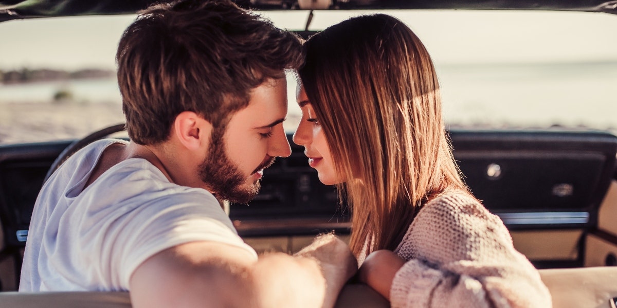 man and woman kissing in front seat of car