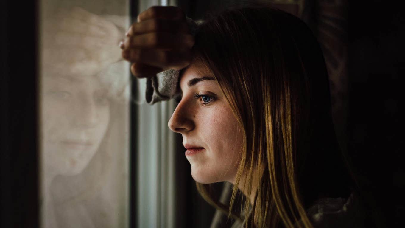 Hurt woman looking out window 