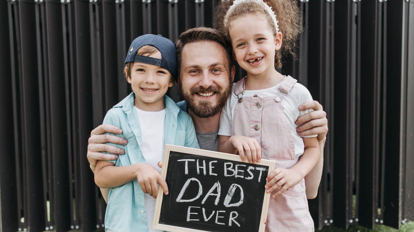 father with kids holding best dad ever sign