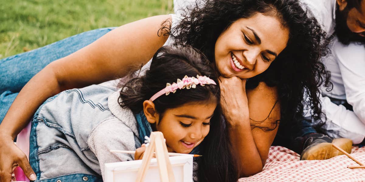 mom and daughter look at her art on picnic blanket 