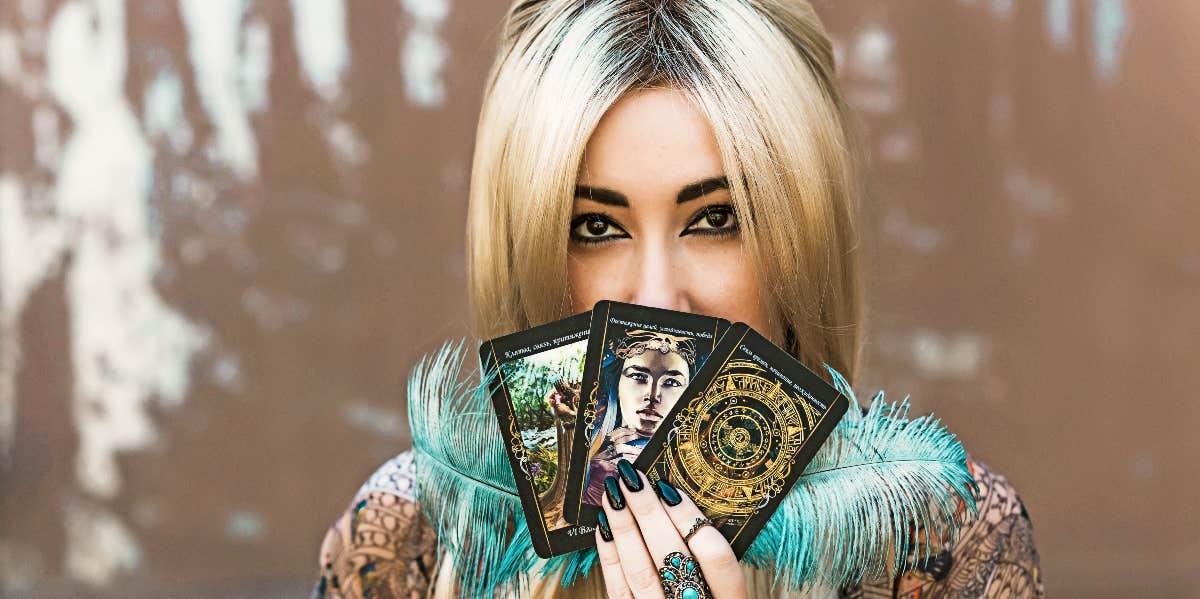 Tarot morning routine Woman peeking over three tarot cards.