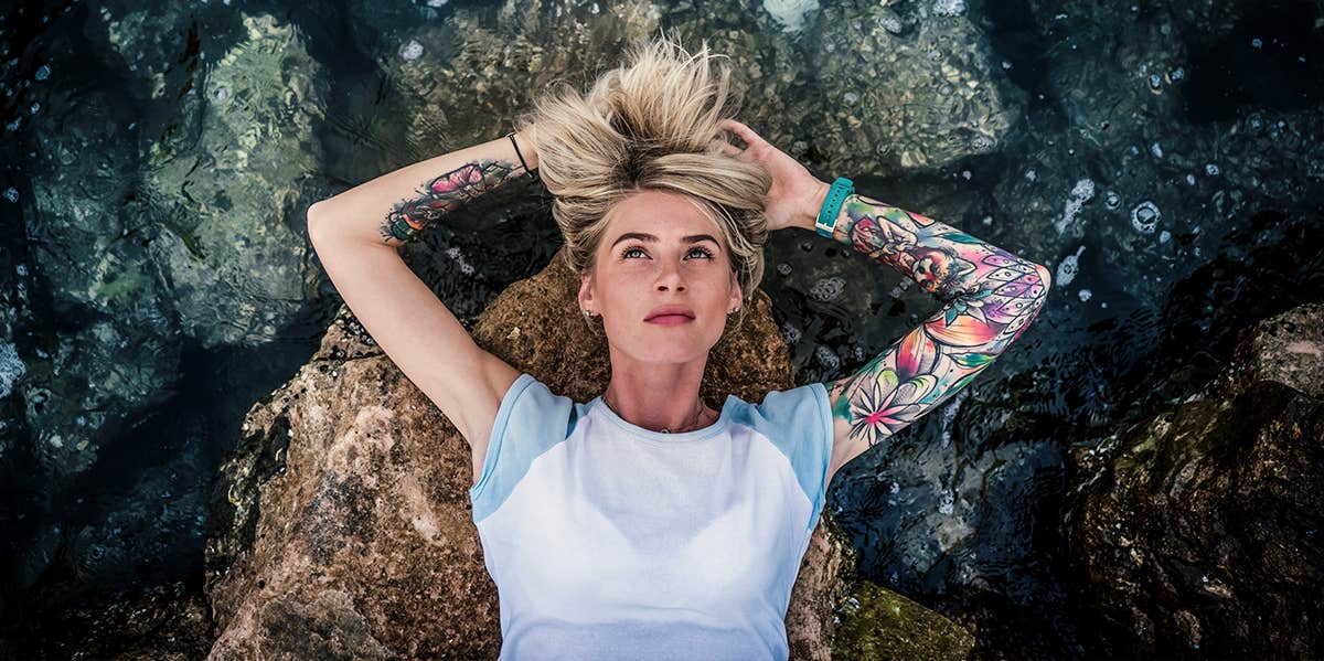 tattooed woman laying in water