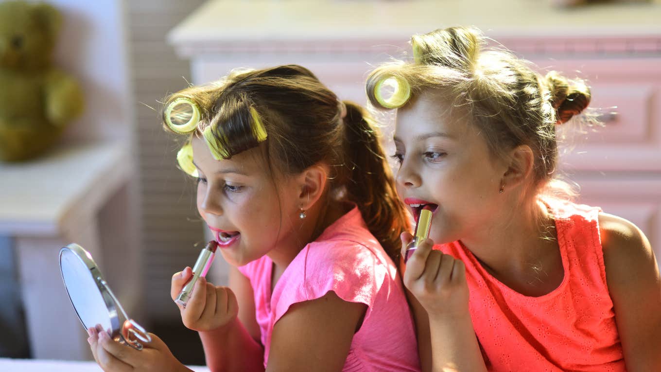 Teacher Accuses Young Girls Of Focusing More On Beauty Than Schoolwork two girls putting lipstick on with curlers in their hair