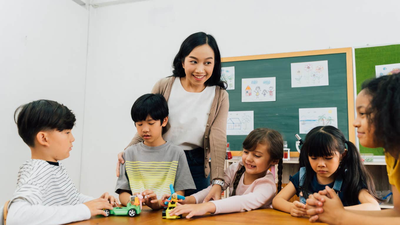 teacher helping students with assignments in classroom