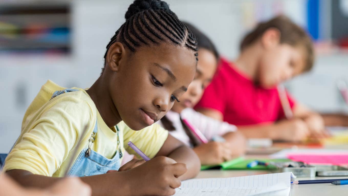 student writing at desk in classroom