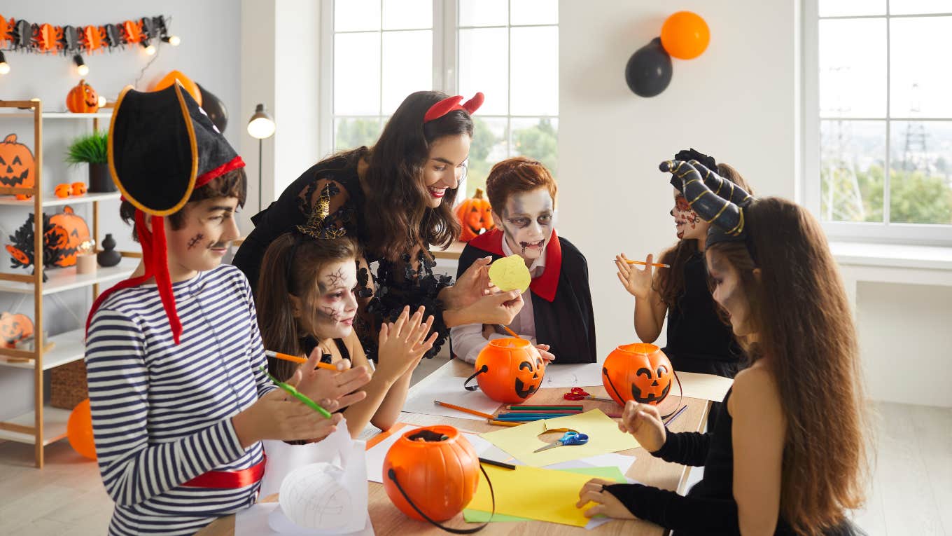 teacher and kids dressed as pirate, witches and vampire having fun Halloween class and cutting out paper