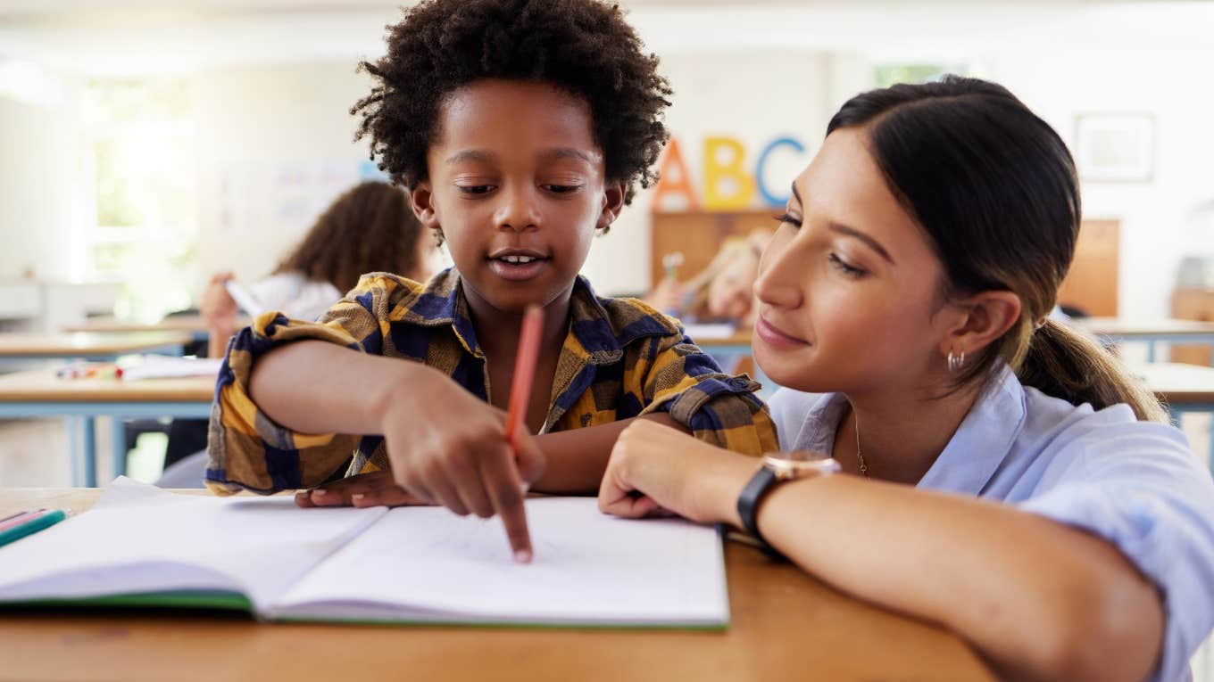 teacher helping student with work in classroom