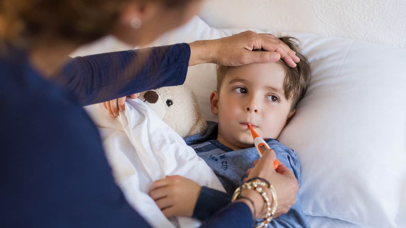 mom taking the temperature of her sick son