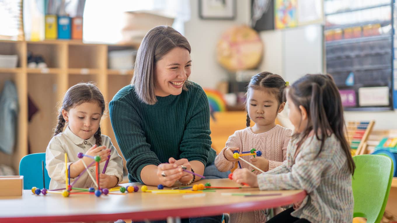 teacher smiling at students playing with educational toys at their desks