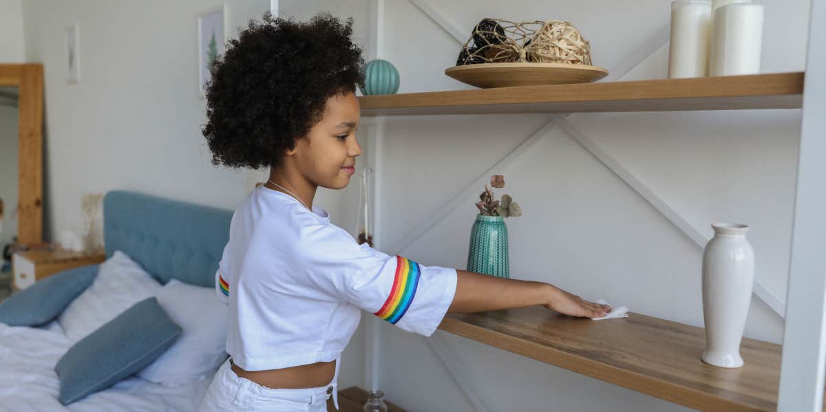 Young girl cleaning a shelf in an apartment