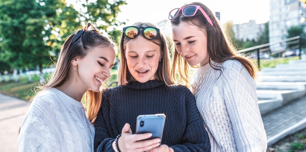 three teenage girls looking at a smartphone