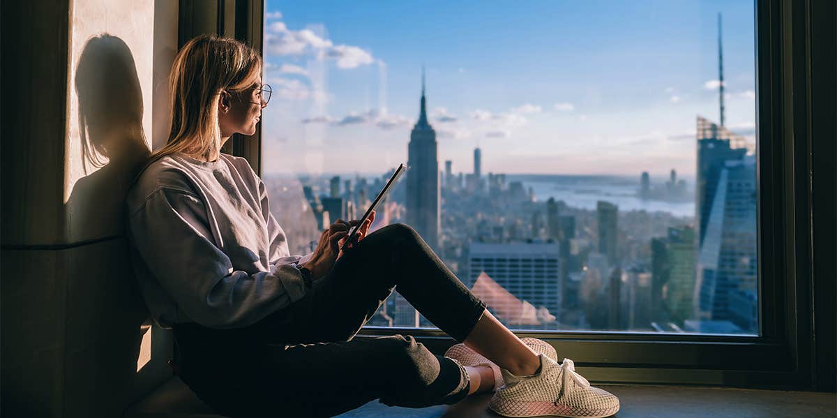 woman sitting by window overlooking city