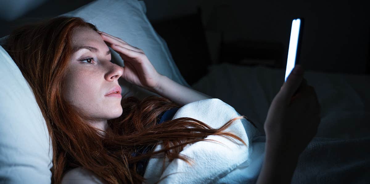 woman looking at phone in bed