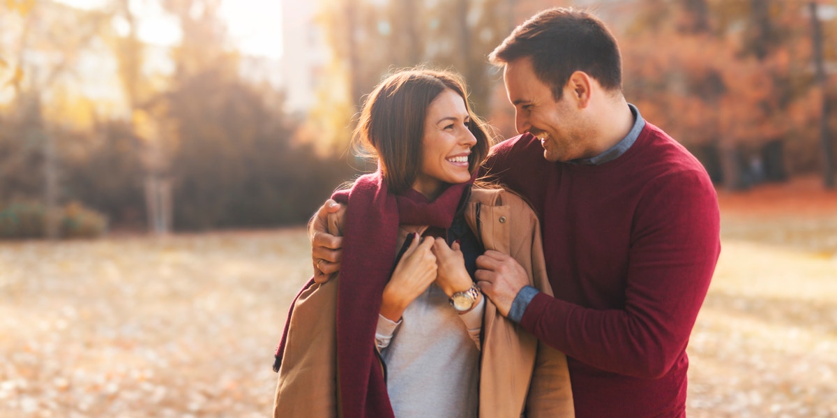 man putting jacket on woman