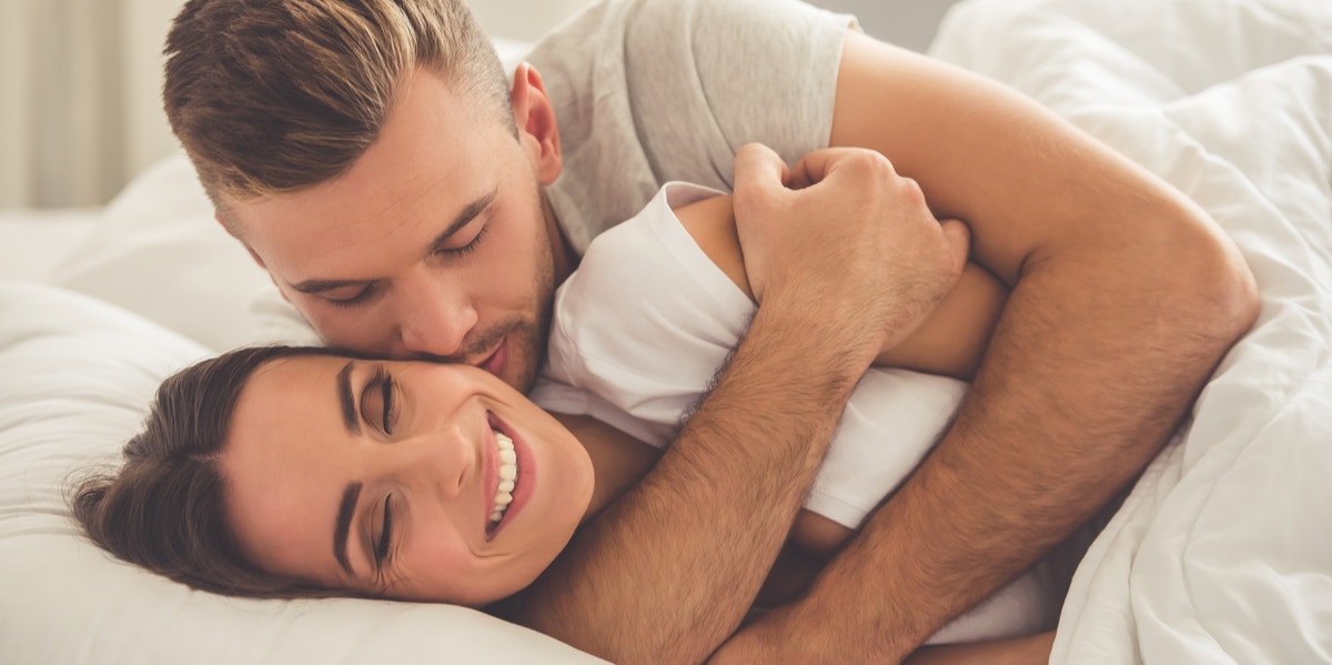 man and woman cuddling in bed