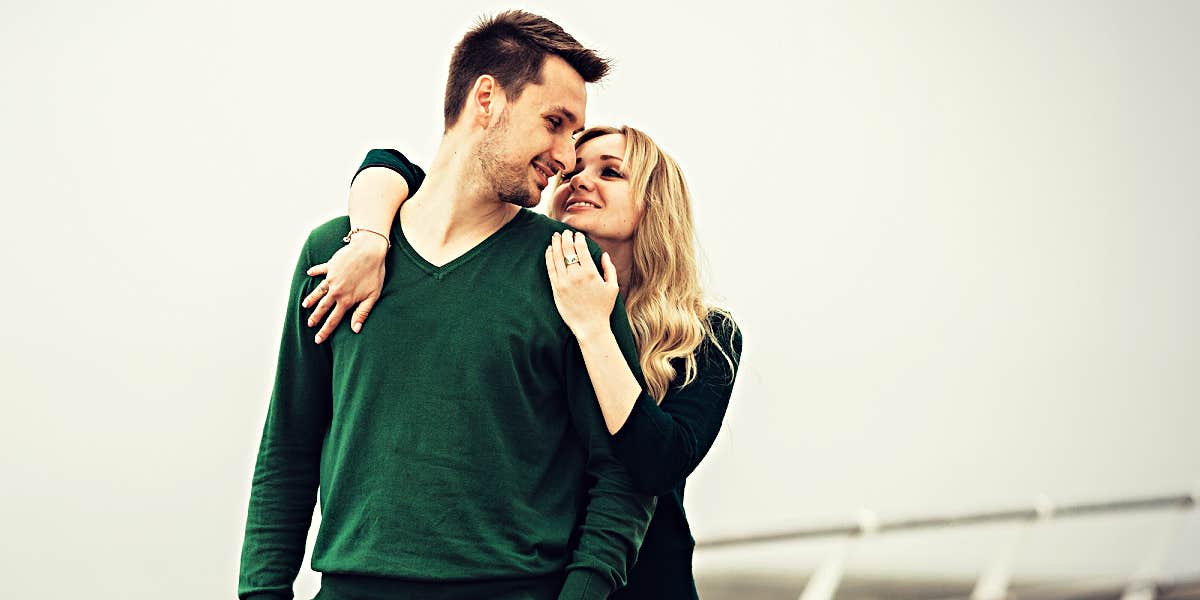 couple hugging on the ship of a deck, man in a vibrant green sweater