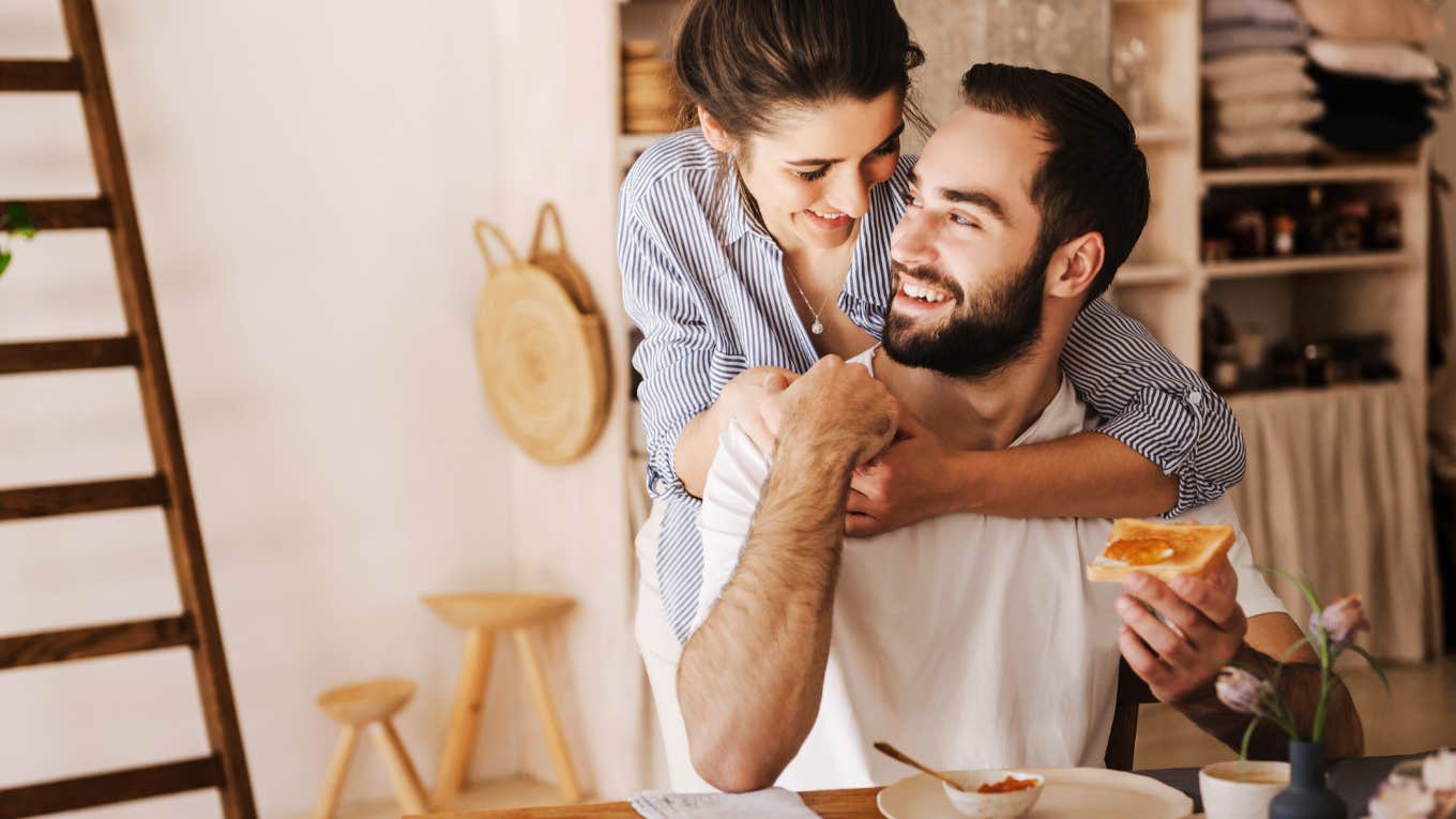 Couple sitting at breakfast table having a sweet moment, hugging