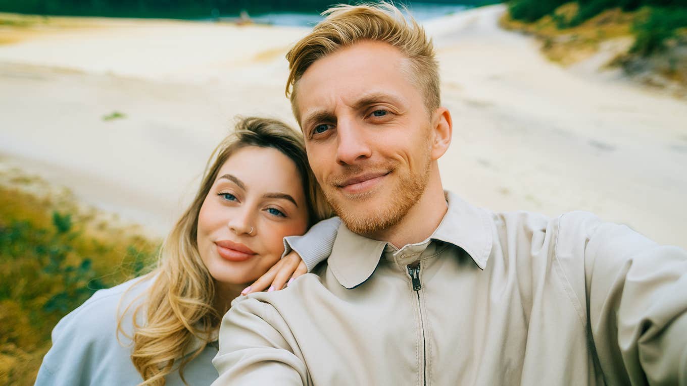 Young couple making selfie photo in travel trip near forest lake.