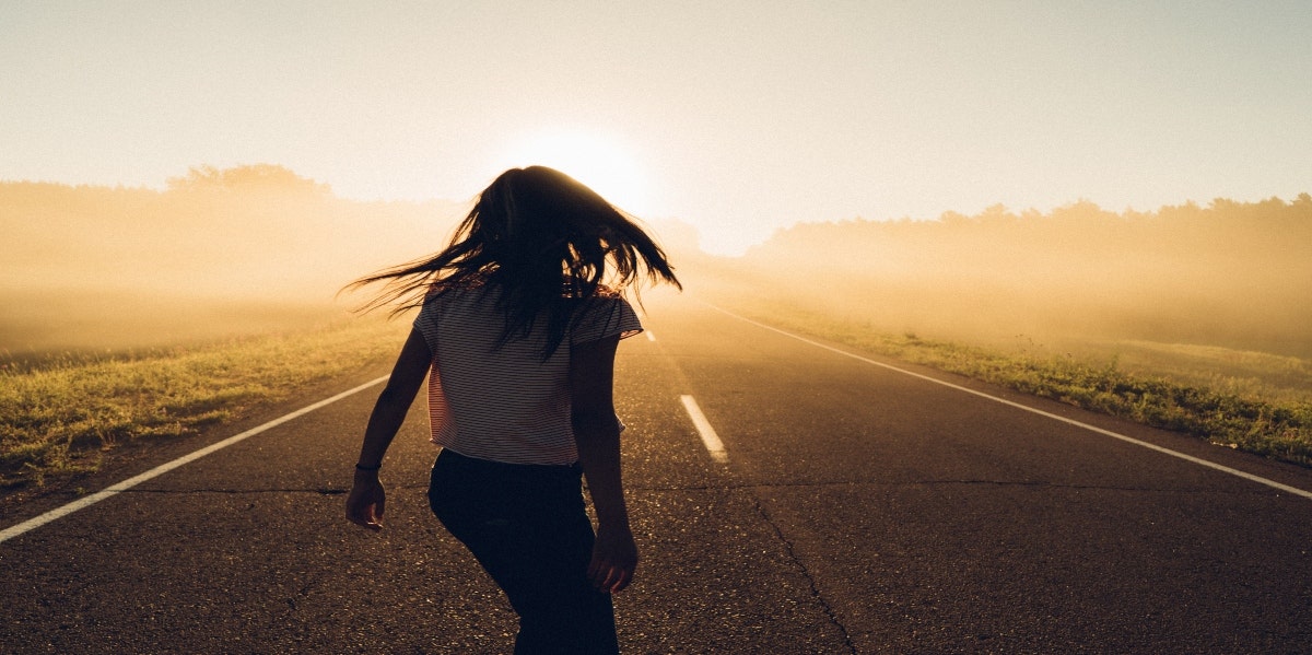 woman walking away desert road