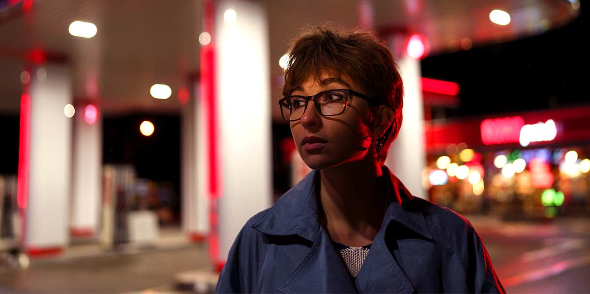 anxious woman at night near gas station