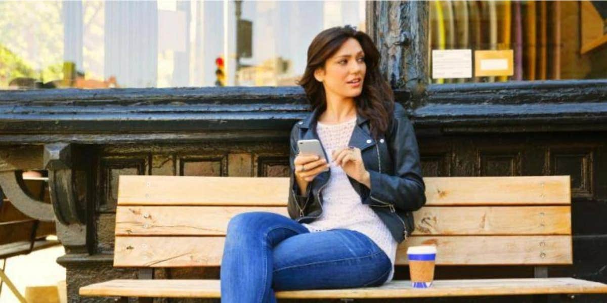 Woman sending text message sitting on a bench