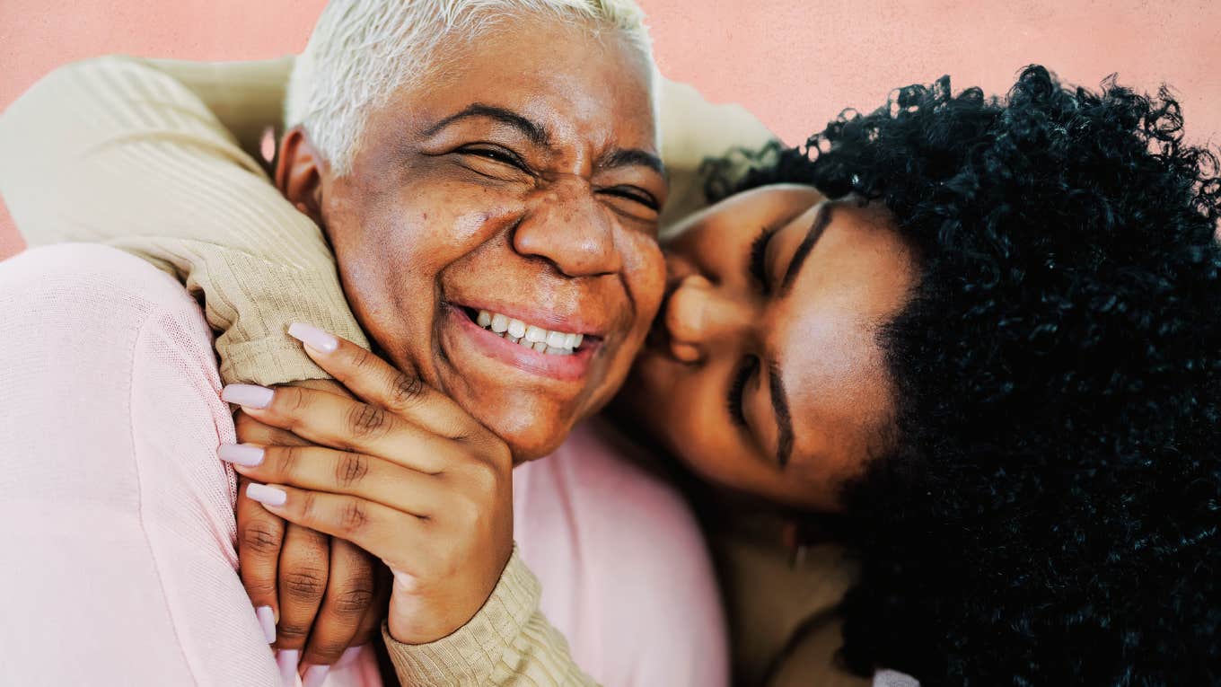 Adult daughter giving her mother a kiss on the cheek